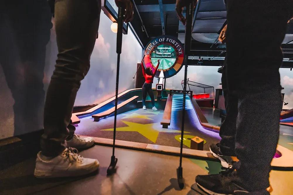 A shot of someone winning a free drink from the Wheel of Fortune hole at Puttshack